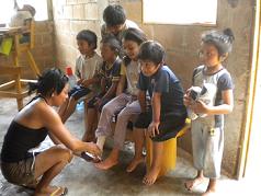  Children anxiously wait their turn to be fitted with tennis shoes donated by the SAIL group