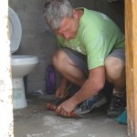 Larry uses a hand chisel to smooth the concrete floor of the bathroom. 